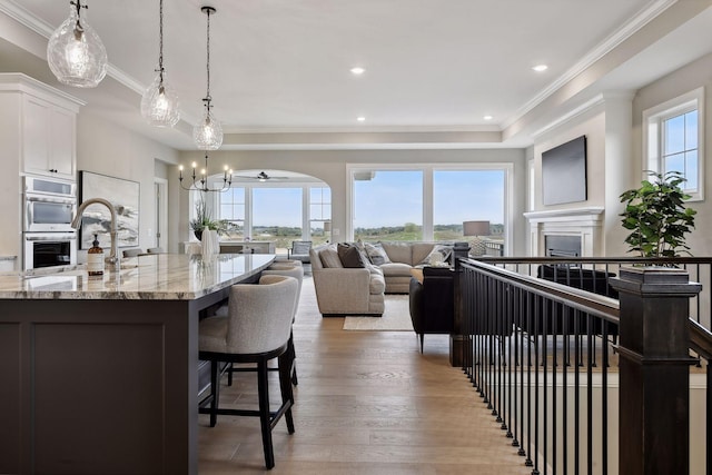 kitchen with crown molding, light stone countertops, wood-type flooring, and hanging light fixtures