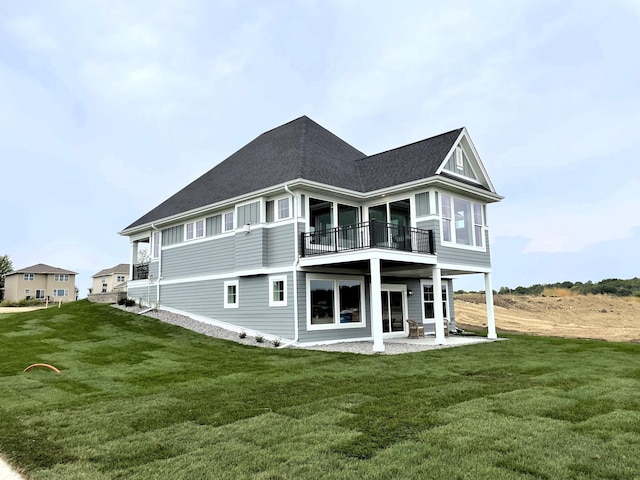 rear view of property featuring a patio area, a lawn, and a balcony