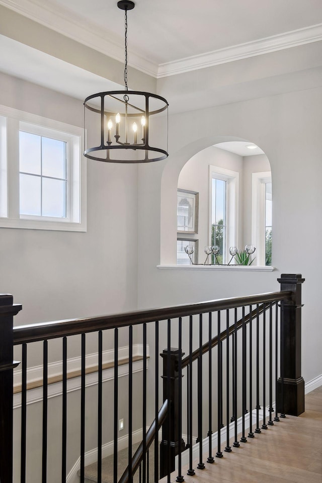 corridor featuring ornamental molding, a chandelier, hardwood / wood-style flooring, and plenty of natural light