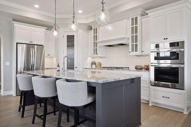 kitchen featuring white cabinets, stainless steel appliances, and a center island with sink