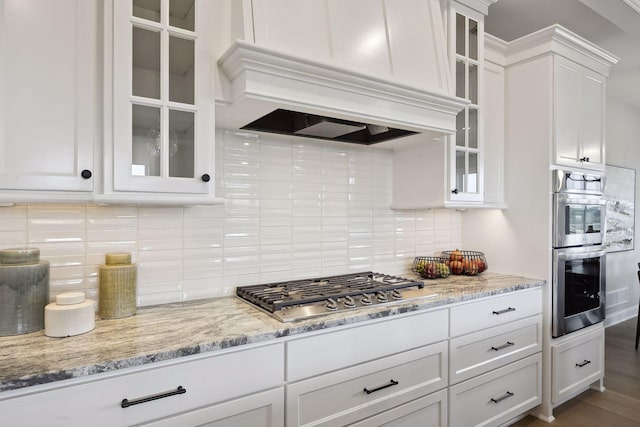 kitchen featuring decorative backsplash, white cabinets, appliances with stainless steel finishes, light stone counters, and dark hardwood / wood-style flooring