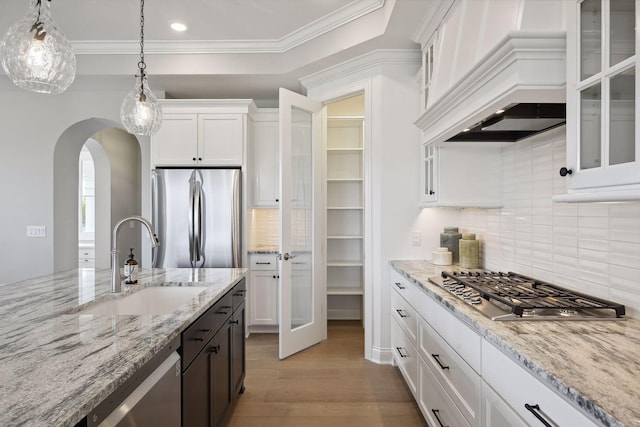 kitchen with tasteful backsplash, appliances with stainless steel finishes, hanging light fixtures, white cabinetry, and light hardwood / wood-style floors