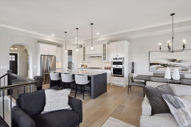 kitchen with light hardwood / wood-style floors, stainless steel appliances, pendant lighting, and white cabinets