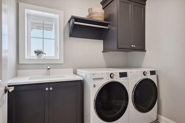 clothes washing area with sink, washer and dryer, and cabinets