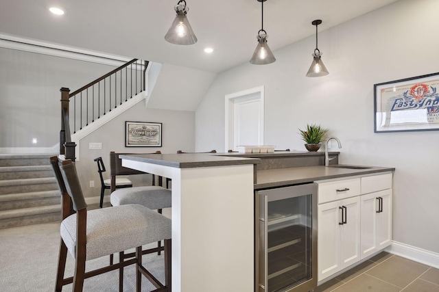 kitchen with kitchen peninsula, wine cooler, white cabinets, a breakfast bar area, and pendant lighting