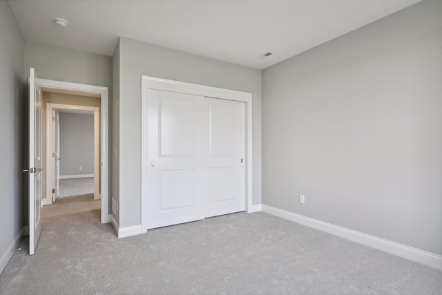 unfurnished bedroom featuring a closet and light carpet