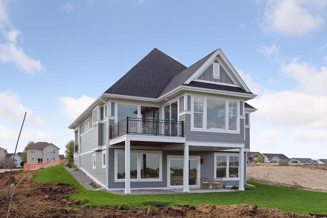 rear view of house featuring a balcony, a yard, and a patio area