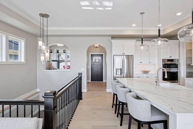 9155 Mills Dr, Chanhassen, MN 55317 - kitchen featuring light wood-style flooring, a wealth of natural light, a sink, stainless steel appliances, and white cabinets