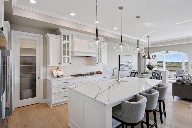 9155 Mills Dr, Chanhassen, MN 55317 - kitchen with light stone counters, a sink, a kitchen bar, white cabinetry, and backsplash