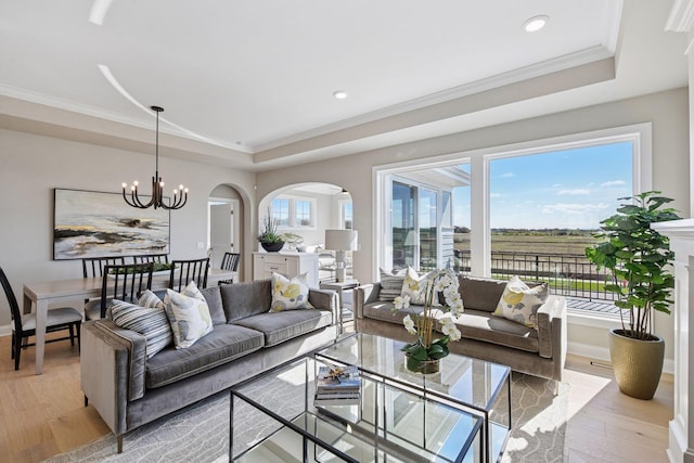 9155 Mills Dr, Chanhassen, MN 55317 - living area with a tray ceiling, a notable chandelier, arched walkways, light wood-style floors, and ornamental molding