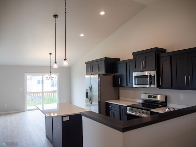 kitchen with light hardwood / wood-style floors, decorative light fixtures, lofted ceiling, and appliances with stainless steel finishes