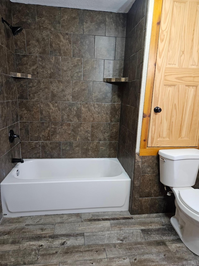 bathroom featuring hardwood / wood-style floors, tiled shower / bath combo, toilet, and tile walls