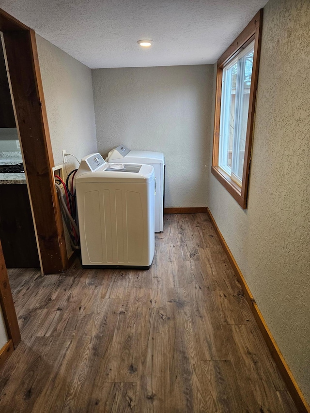 laundry area with wood-type flooring, a textured ceiling, and separate washer and dryer