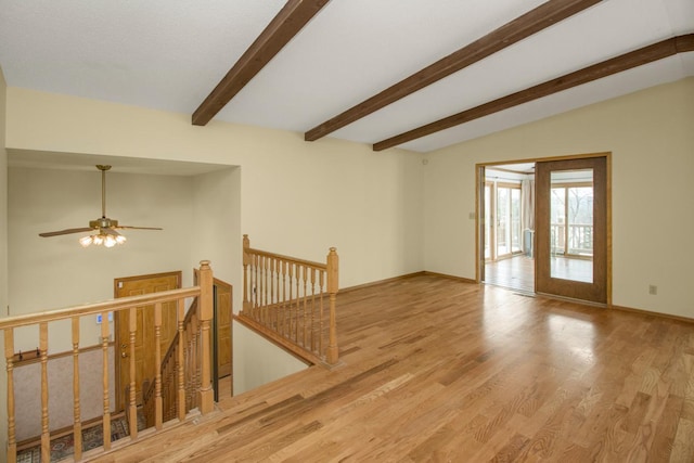 spare room featuring vaulted ceiling with beams and light hardwood / wood-style floors