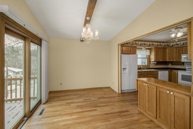 kitchen with pendant lighting, sink, white appliances, lofted ceiling, and light wood-type flooring