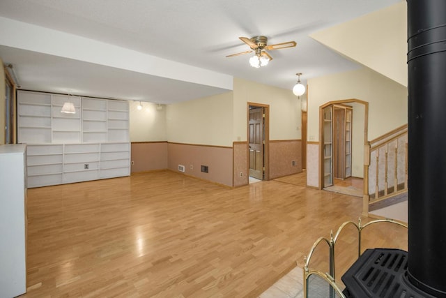 interior space with a wood stove, ceiling fan, and light hardwood / wood-style flooring