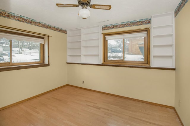 empty room featuring ceiling fan, plenty of natural light, and light wood-type flooring