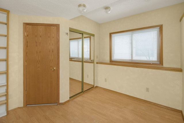 unfurnished bedroom featuring light hardwood / wood-style floors, a closet, and a textured ceiling