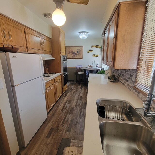 kitchen with white appliances, ceiling fan, dark wood-type flooring, and decorative backsplash