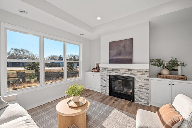 living room with a stone fireplace and light wood-type flooring