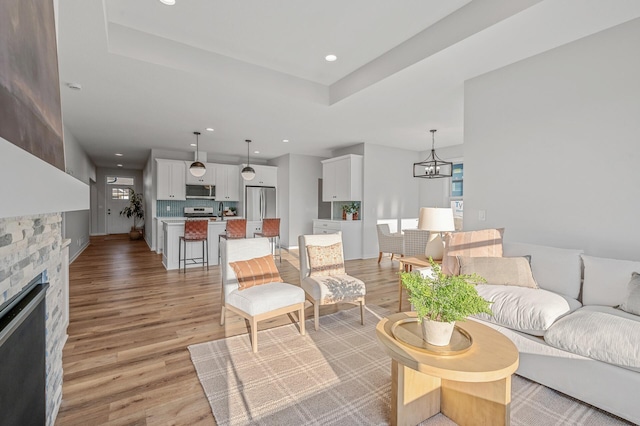 living room featuring a chandelier, light wood-type flooring, and a fireplace