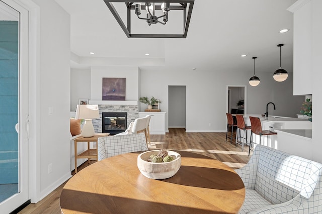 living room with light hardwood / wood-style floors, a stone fireplace, and sink