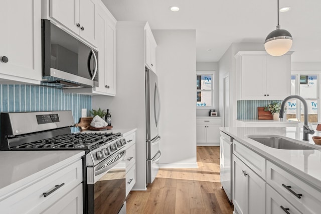 kitchen featuring decorative backsplash, light hardwood / wood-style flooring, stainless steel appliances, sink, and white cabinetry