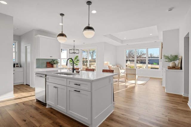 kitchen with dishwasher, sink, an island with sink, and white cabinets