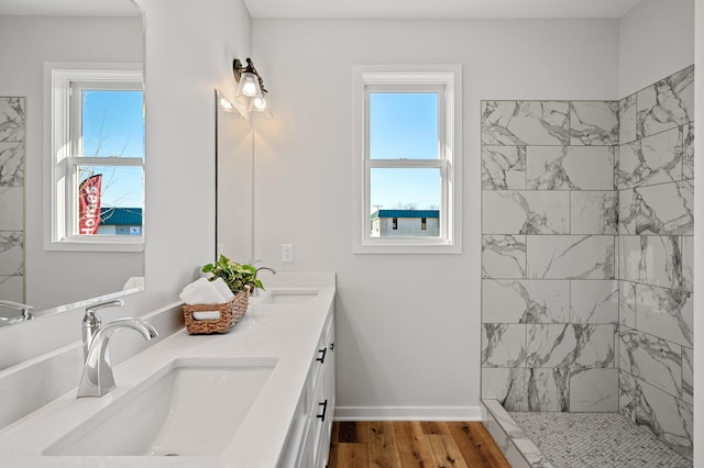 bathroom with vanity, a tile shower, wood-type flooring, and plenty of natural light