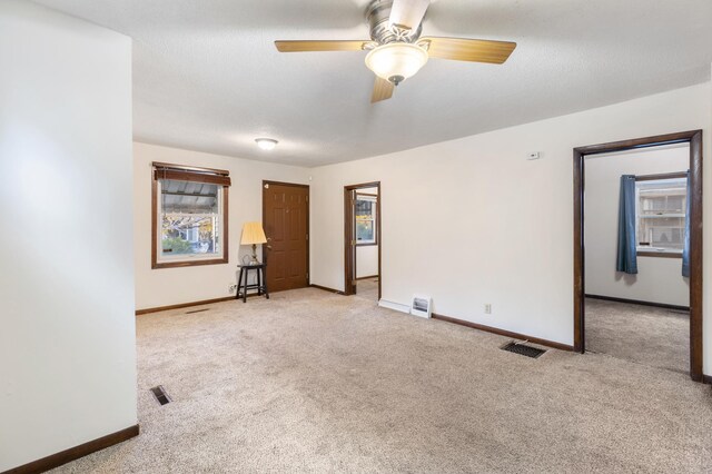 empty room with ceiling fan, light carpet, and a textured ceiling