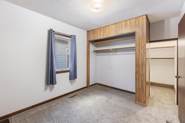 unfurnished bedroom with light carpet, a textured ceiling, and a closet