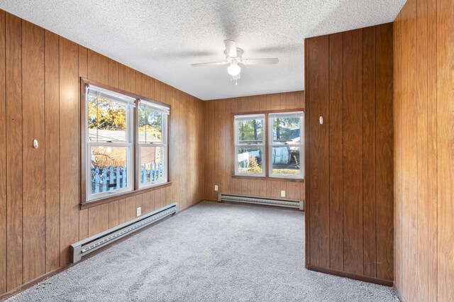 spare room with light carpet, a textured ceiling, ceiling fan, and a baseboard heating unit