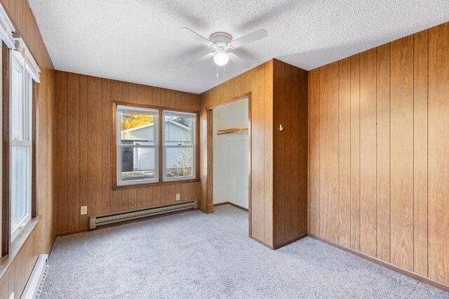 unfurnished bedroom featuring ceiling fan, baseboard heating, light carpet, and a closet