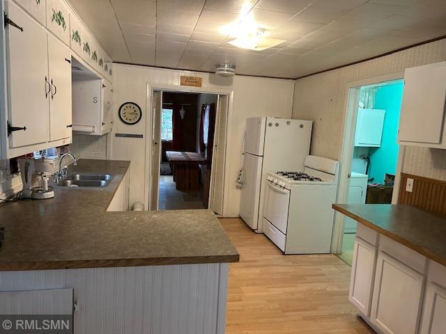 kitchen featuring light hardwood / wood-style floors, white cabinetry, white gas stove, and sink