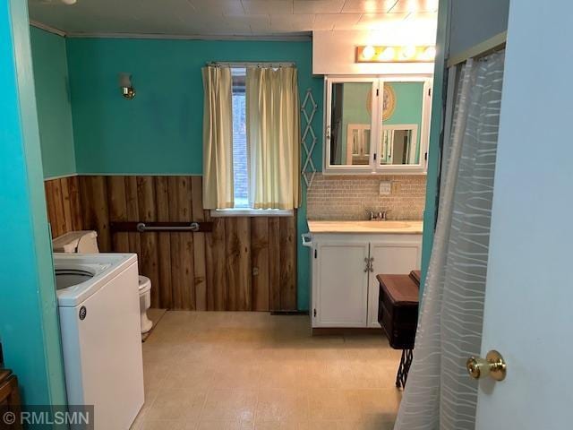 bathroom with decorative backsplash, toilet, washer / clothes dryer, wooden walls, and vanity