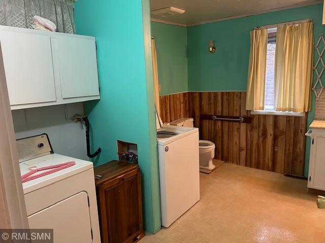 washroom featuring washer / dryer, crown molding, cabinets, and wooden walls