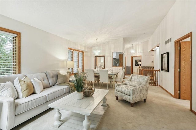 carpeted living room with an inviting chandelier