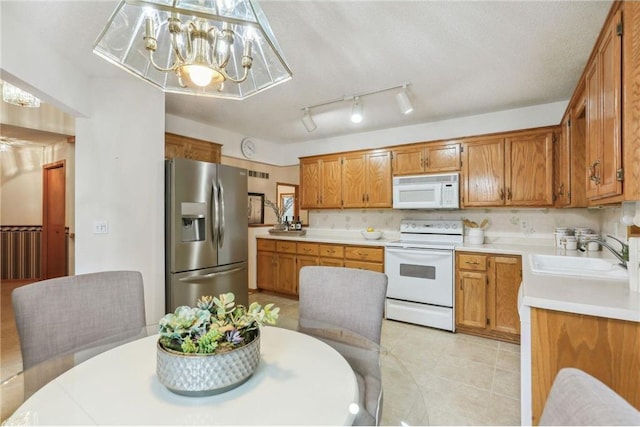 kitchen with sink, a textured ceiling, hanging light fixtures, white appliances, and a chandelier