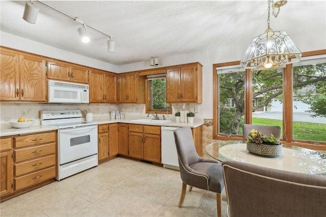 kitchen featuring light tile patterned flooring, white appliances, hanging light fixtures, sink, and a chandelier