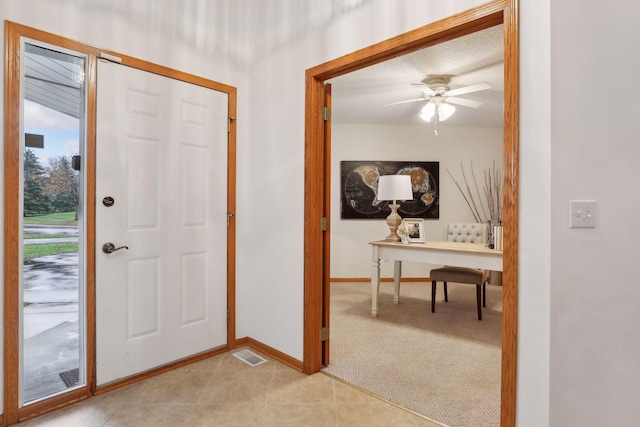 tiled entryway with a textured ceiling and ceiling fan