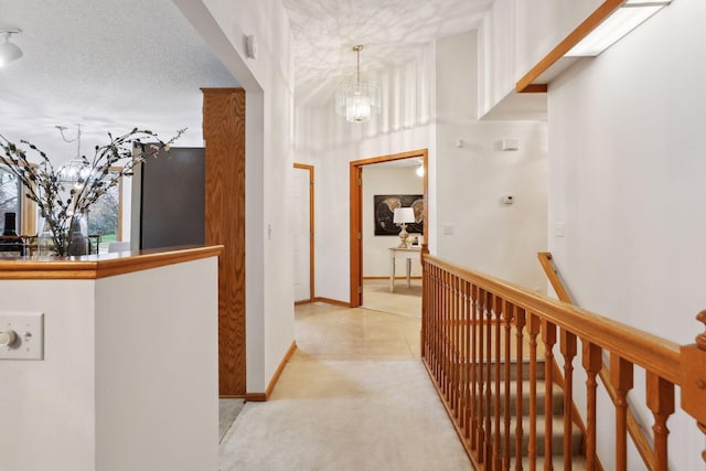 corridor with a chandelier, a textured ceiling, and light carpet