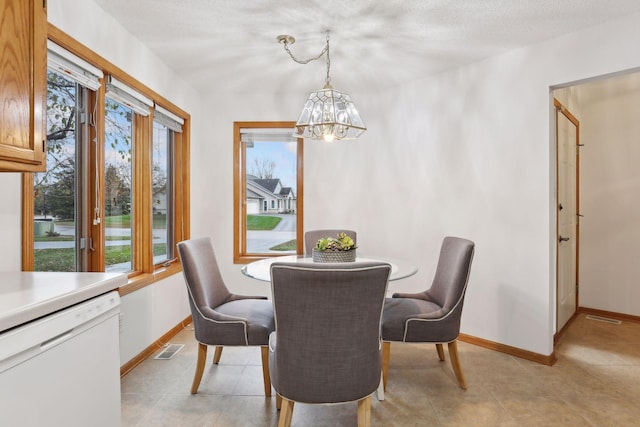 tiled dining space with a textured ceiling and a notable chandelier