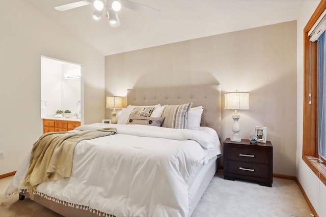 carpeted bedroom with ensuite bath, lofted ceiling, and ceiling fan