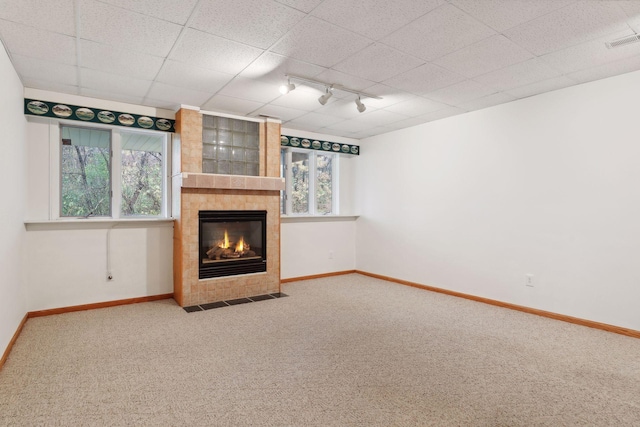 unfurnished living room with carpet flooring, a fireplace, and rail lighting