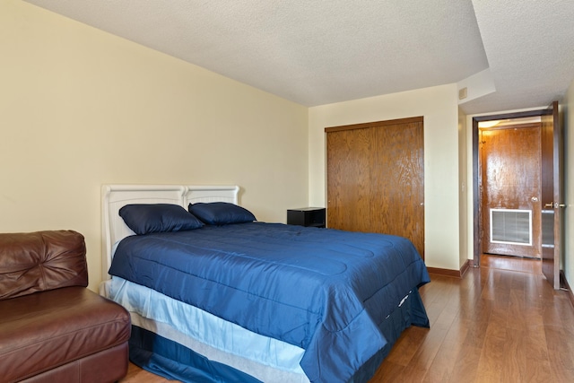 bedroom with hardwood / wood-style floors, a textured ceiling, and a closet