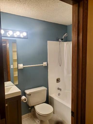 full bathroom featuring a textured ceiling, vanity, shower / tub combination, tile patterned flooring, and toilet