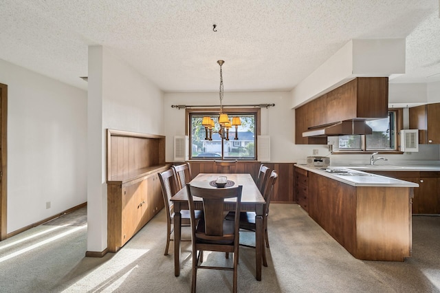 dining room with sink, a chandelier, a textured ceiling, and light colored carpet