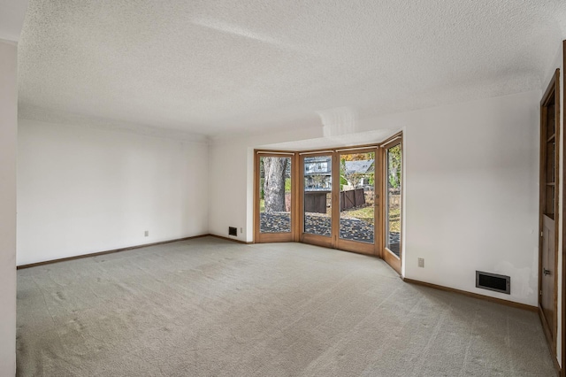 carpeted empty room featuring a textured ceiling