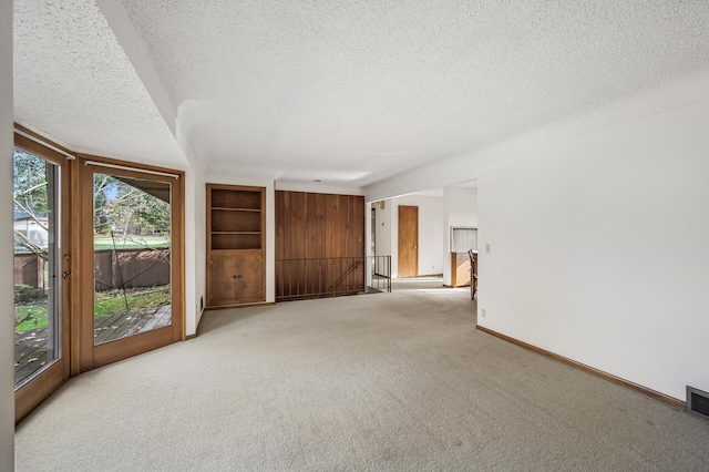 spare room featuring a textured ceiling and light carpet