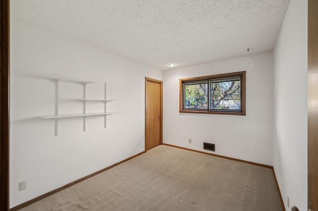 carpeted spare room featuring a textured ceiling